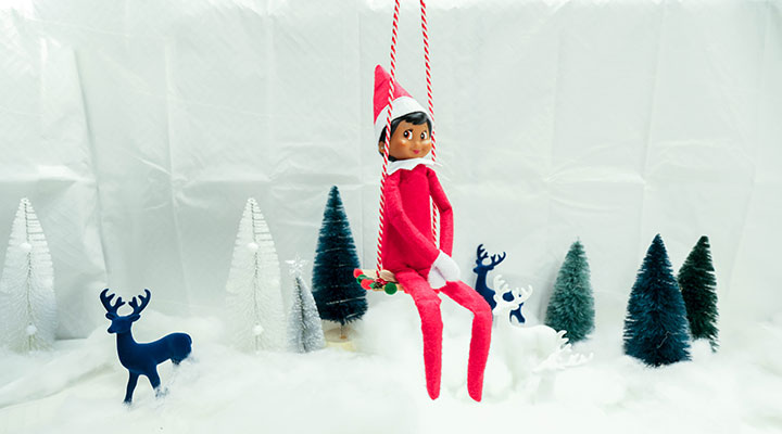 elf on shelf taking in the outdoors on a swing